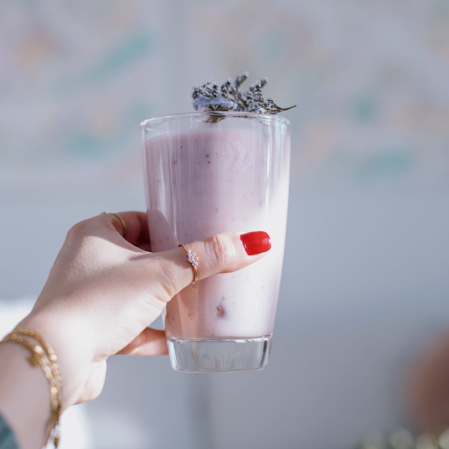 female holding tall glass of a thick pink smoothie